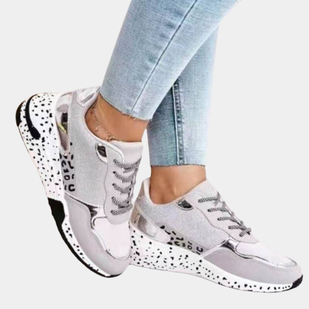 Dames sneakers in goud en beige met glinsterende details, zwarte en witte zool, en veters. Modieuze sportschoenen voor casual en sportieve outfits.